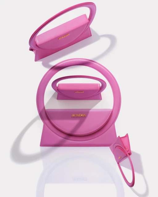 Multiple pink leather handbags with a round handle are displayed against a light background, highlighting the design and color.
