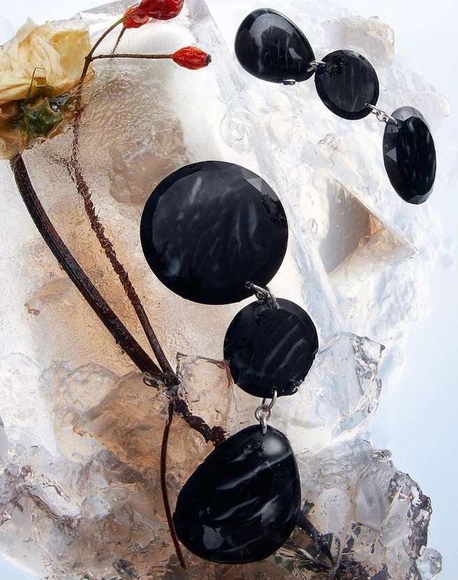 Fashionable black gemstone necklace on a textured background with dried flowers and icy accents in an eye-catching still-life.