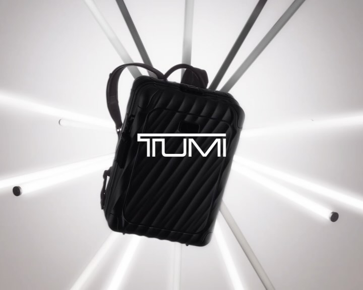 Black quilted backpack with the white TUMI logo in the center floating against a white background and lit by white light beams.