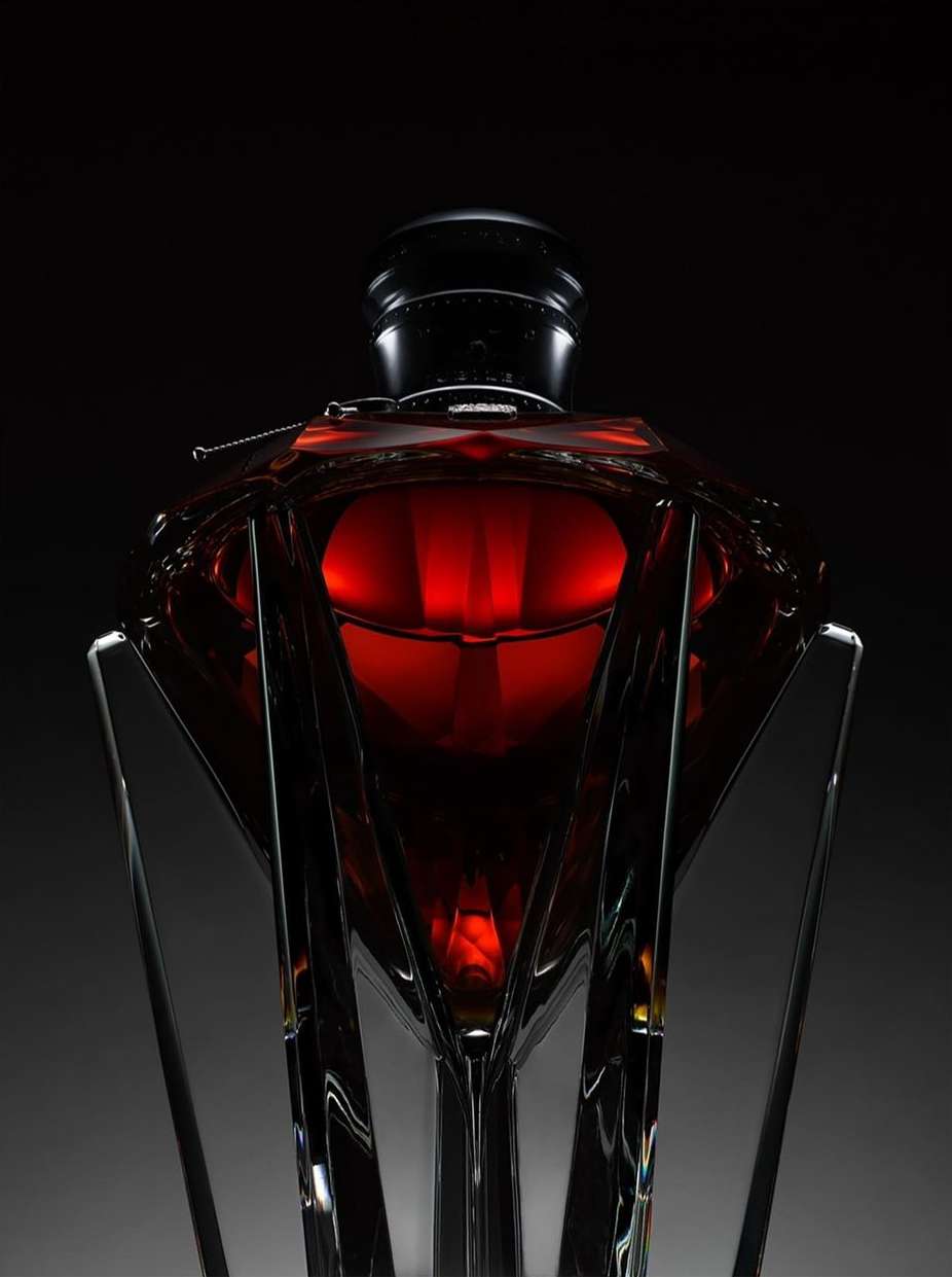 Elegant decanter filled with red liquid displayed against a dark background highlighting its unique shape and the liquid's color.