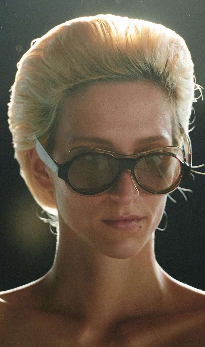 Close-up portrait of a woman wearing rounded sunglasses and voluminous blonde hair, captured by Talia Chetrit
