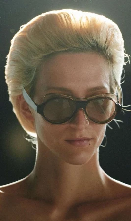 Close-up portrait of a woman wearing rounded sunglasses and voluminous blonde hair, captured by Talia Chetrit