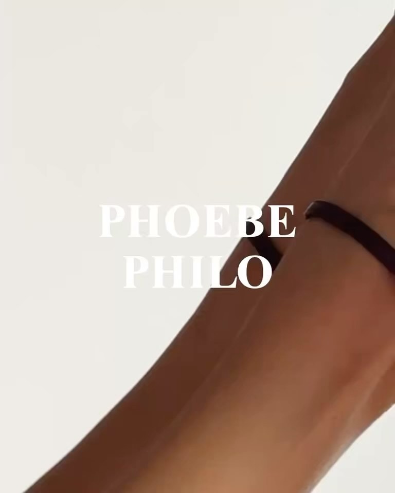 Closeup of fair skin forearm and hand against a white background, with a thin black choker bracelet on the wrist, and brand text overlay.