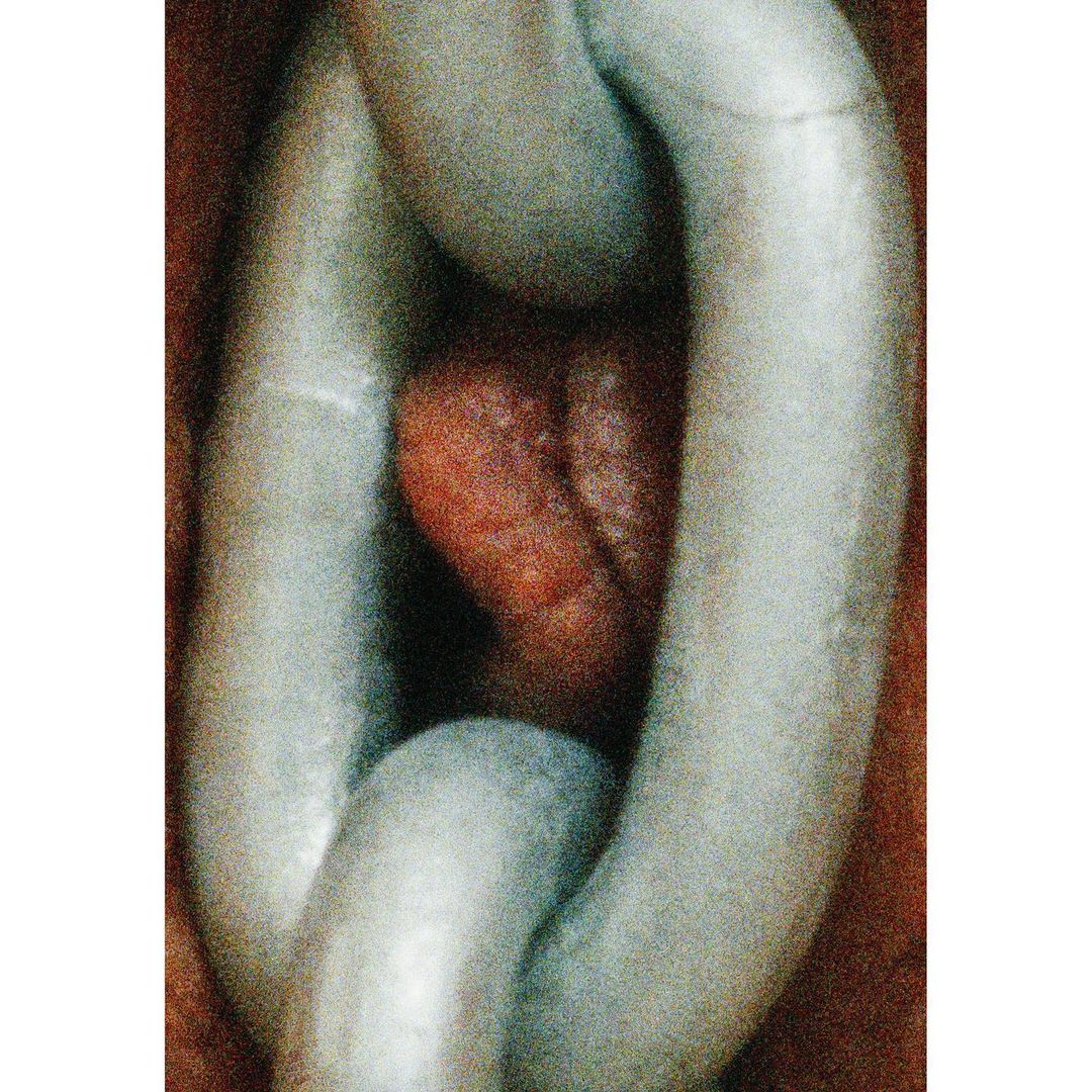 Close-up of a metal chain link featuring orange-red color cast in the center, highlighting industrial strength and abstract composition.