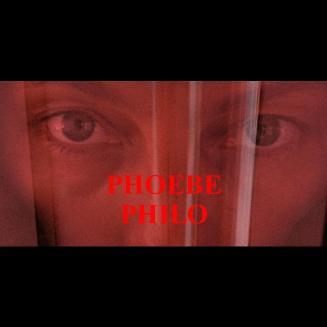 Close-up of a person's face partially obscured by a sheer material, with the text 'PHOEBE PHILO' overlaid in red.