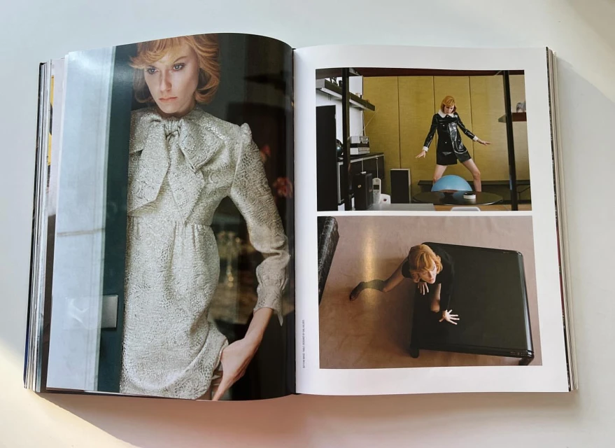 Fashion editorial in open magazine features a woman in a silvery dress with a bow, plus black mini-dress & a woman emerging from a box.