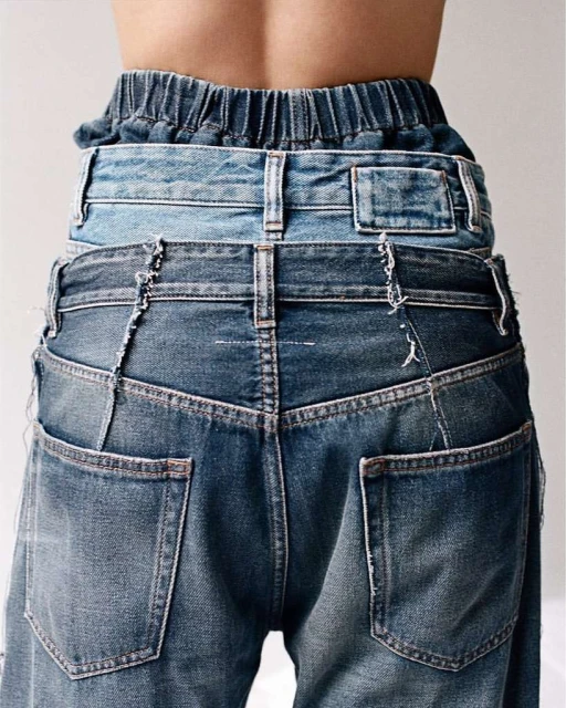 Rear view of a person wearing layered blue denim jeans, showcasing innovative and stylish fashion design against a plain background.