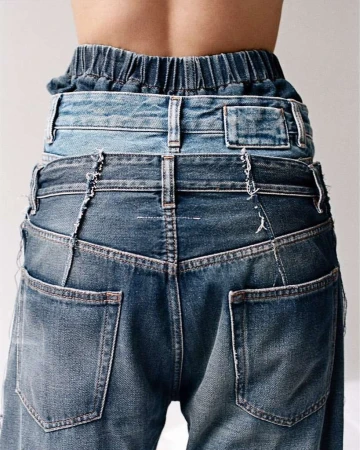 Rear view of a person wearing layered blue denim jeans, showcasing innovative and stylish fashion design against a plain background.