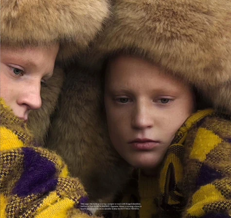 Two individuals wearing large fluffy fur hats and patterned yellow and purple jumpers photographed by Tanya and Zhenya Posternak