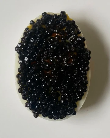 Caviar tops a halved boiled egg, creating a striking contrast between the white egg and the shiny black pearls.