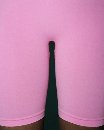 Close-up of person in pink shorts with shadow on dark green background, fashion, athletic wear, fitness apparel, legs.