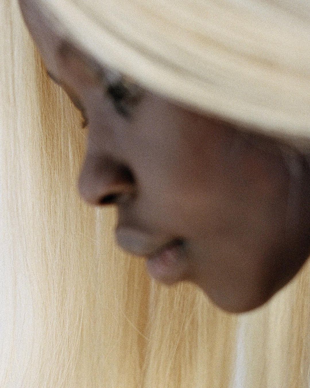 Close-up of an African American adult female with a serene expression, featuring straight blonde hair in a beauty and fashion context.