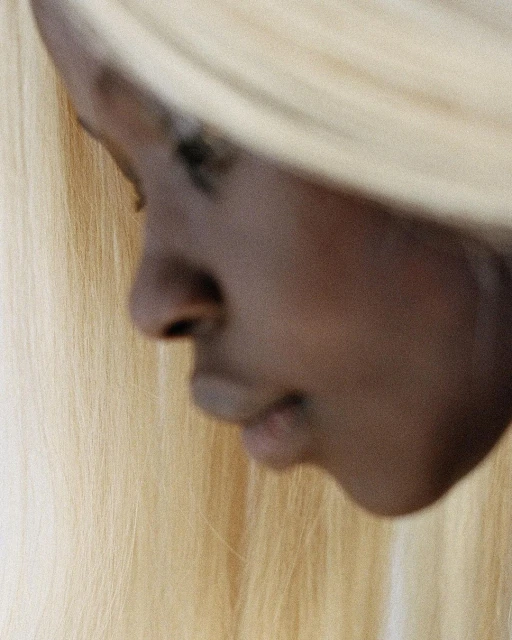 Close-up of an African American adult female with a serene expression, featuring straight blonde hair in a beauty and fashion context.