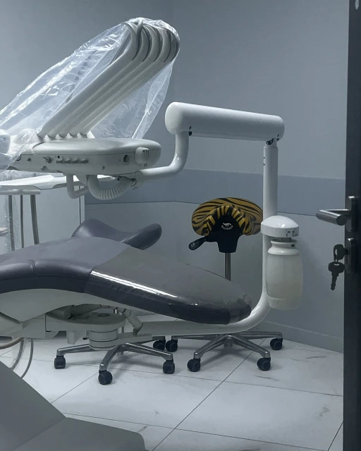 Dental examination room featuring an adjustable chair and overhead light with a white tiled floor in a healthcare setting.
