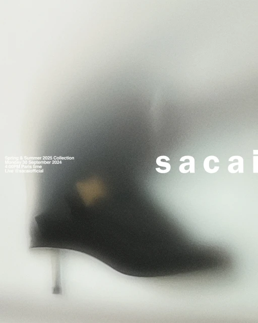 Fashion advertisement featuring a black ankle boot with a metallic heel, blurred against a light grey background with brand typography.