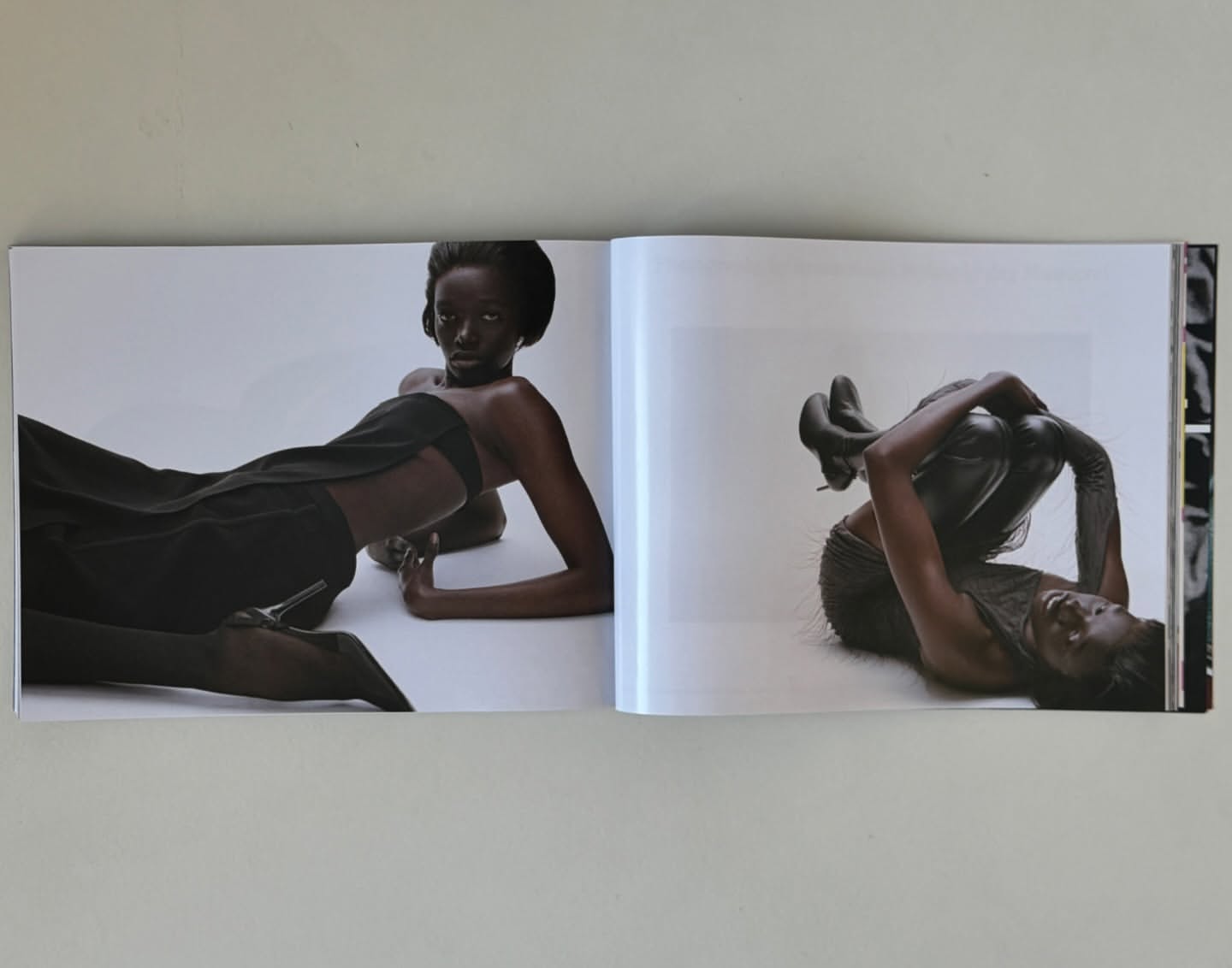 An open magazine showing editorial fashion photography of Black women posing in black outfits against a white background.