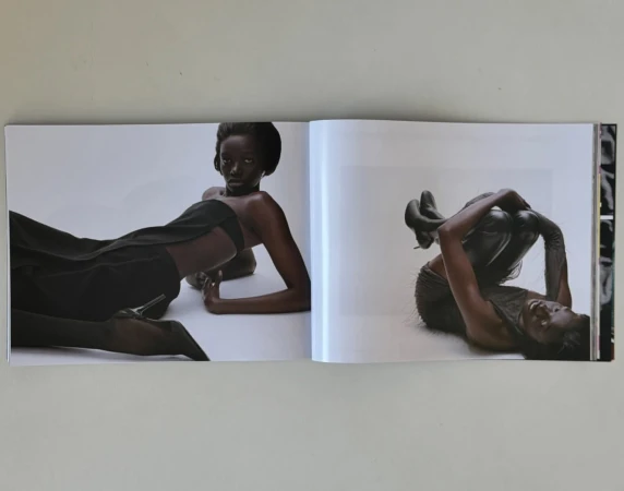 An open magazine showing editorial fashion photography of Black women posing in black outfits against a white background.