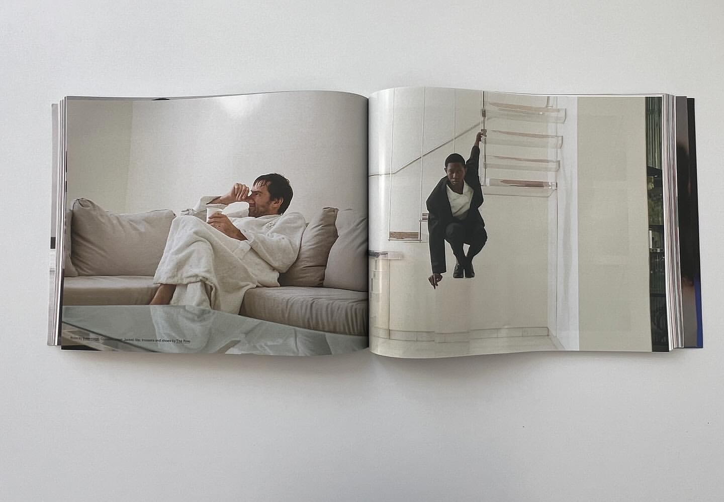 Magazine spread shows an adult male in robe with drink on couch, and a young person in a suit squatting on a stair landing.