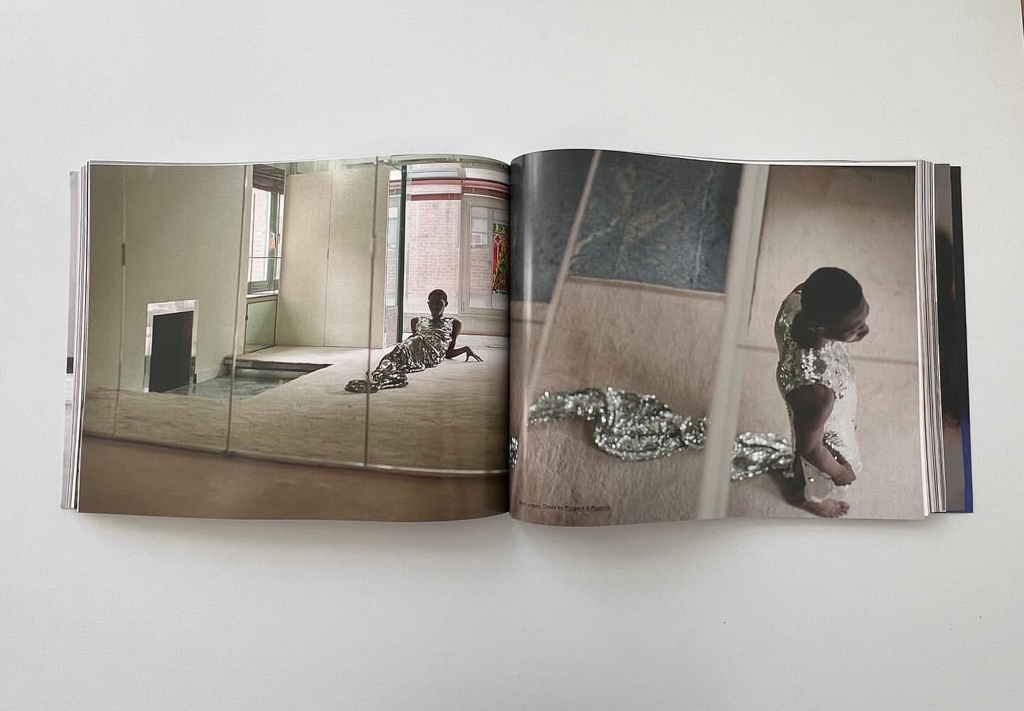 Open magazine spread showing editorial photographs of a person in a glittering sequin dress inside an interior space.