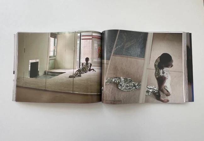 Open magazine spread showing editorial photographs of a person in a glittering sequin dress inside an interior space.
