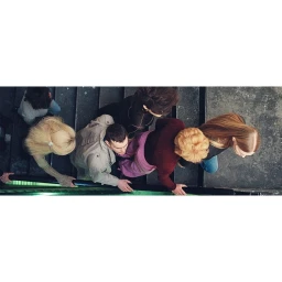 High-angle overhead view of a group of people descending dark stone stairs holding onto a dark railing.