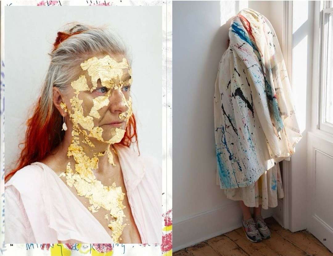 Elderly woman's face is partially covered with gold leaf, while a figure in an adjacent shot is draped in paint-splattered fabric.