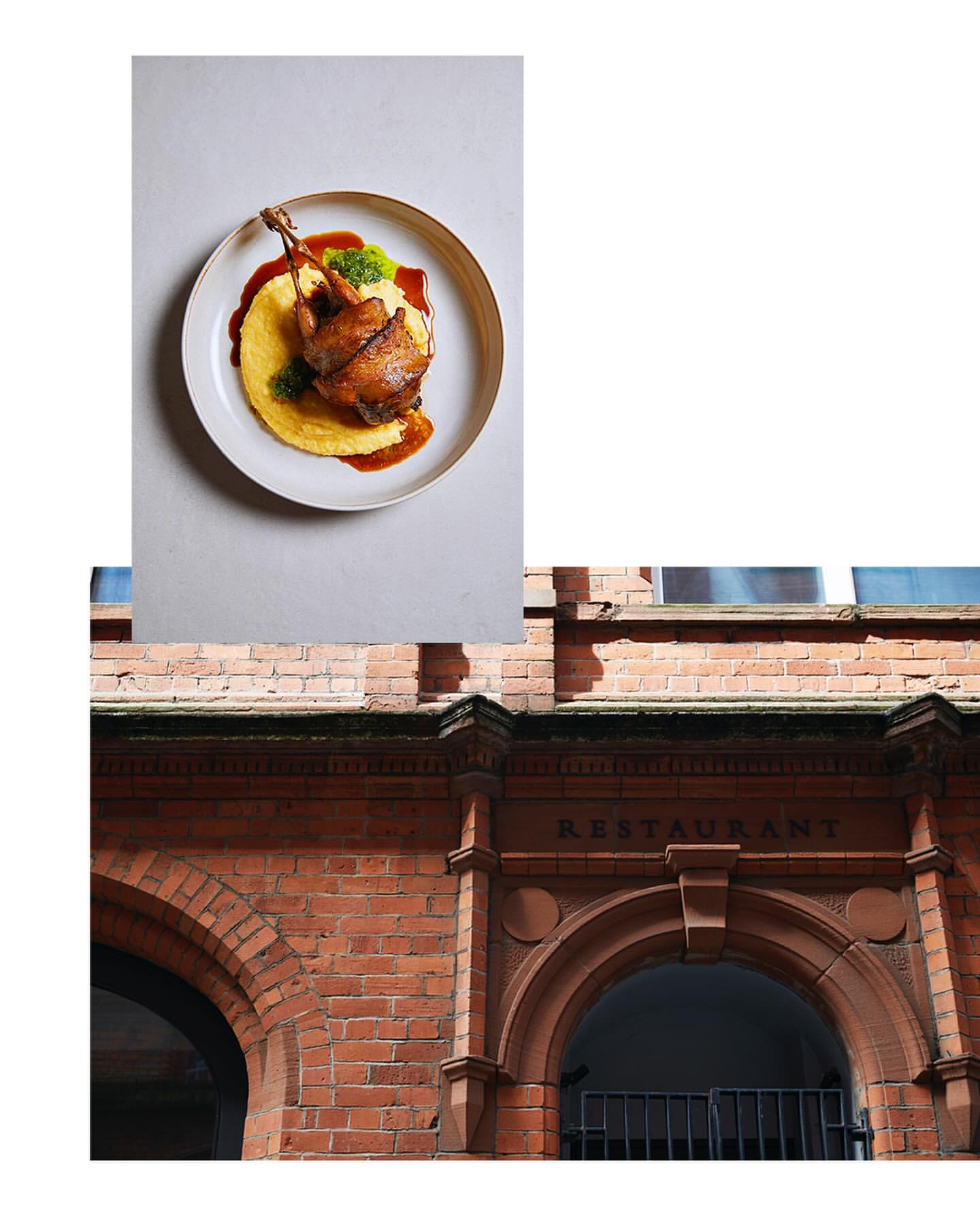 Overhead studio shot showcases duck confit, served on polenta with sauce, elegantly presented on a white plate, near a brick building.