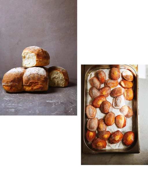 Freshly baked bread and sugared doughnuts sit side-by-side on a gray surface, showcasing golden-brown crusts and powdered sugar.
