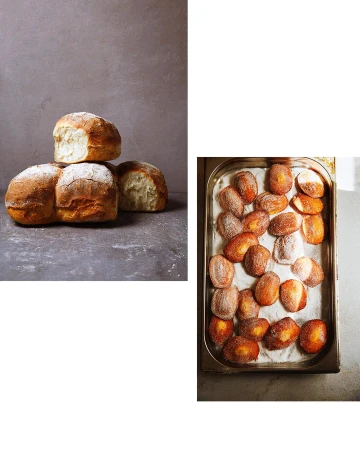 Freshly baked bread and sugared doughnuts sit side-by-side on a gray surface, showcasing golden-brown crusts and powdered sugar.