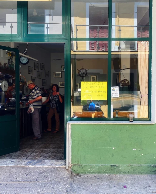 View of an open-door cafe with two people inside, one wearing a striped shirt and another wearing a polka dot shirt.