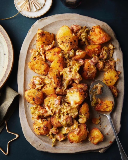 Overhead shot of golden brown potatoes with leeks and cream sauce served on a tan stoneware platter, a festive holiday food.