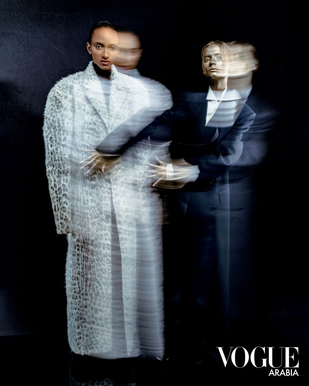 Editorial fashion image by Tarek Mawad showing two models with multiple exposure motion blur against a dark background.