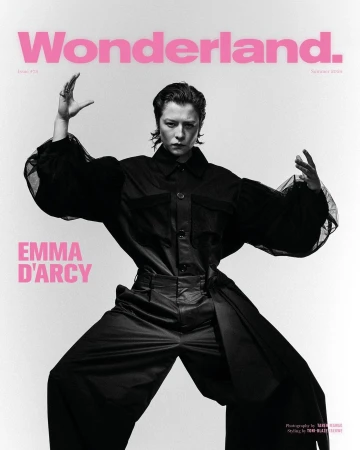 Emma D'Arcy poses on the cover of Wonderland magazine in a wide stance wearing a black jumpsuit against a stark white background.