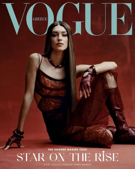 Vogue Greece cover featuring Daisy Edgar-Jones in a red lace dress and matching boots, posing against a reddish-brown backdrop.