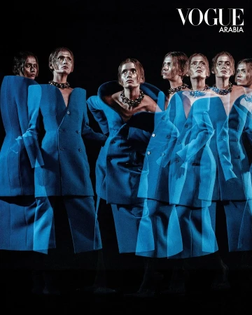 Fashion editorial featuring multiple exposures of a model in a blue suit and chunky necklace, set against a dark background.