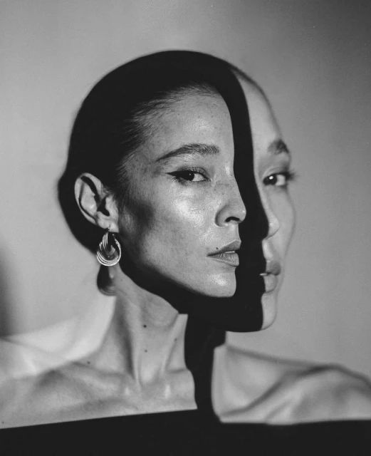Striking black and white portrait of a woman with defined facial features, set against a simple background with dramatic lighting.