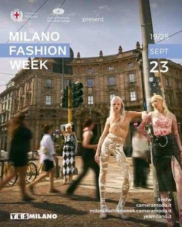 Two fashion models pose in front of a traffic light and historic building in Milan, Italy during Fashion Week. Pedestrians in motion.