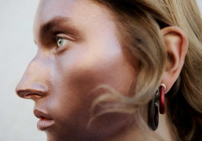 Close-up profile portrait of a woman with bronze-toned skin and hoop earrings by Tassili Calatroni