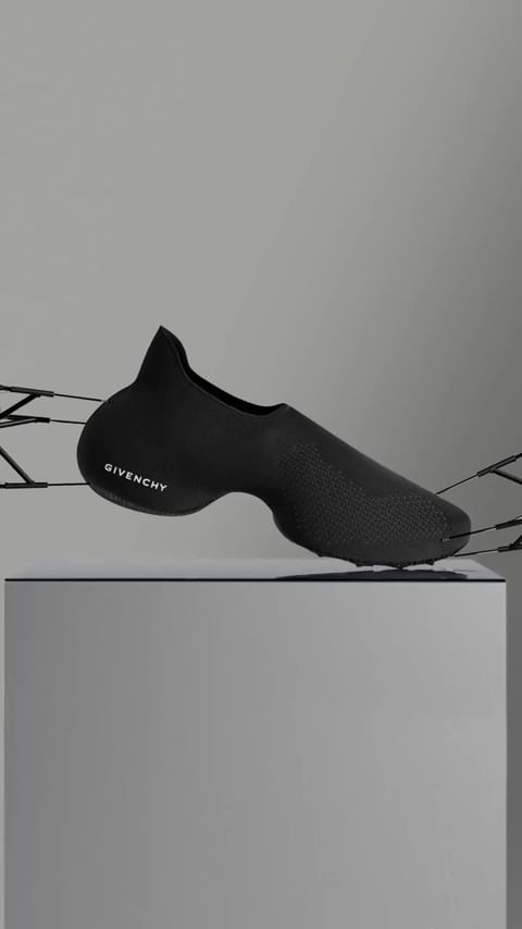 Elevated product shot of a black Givenchy sneaker on a white pedestal against a light grey backdrop, accentuating its modern design.