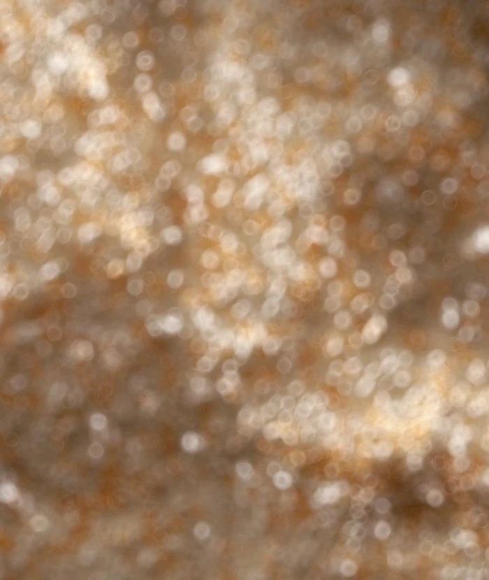 Abstract 3D rendered bokeh light texture in warm golden tones with soft out of focus ring patterns.