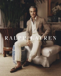 Chris Pine seated on a white sofa in a tailored tan blazer, white shirt, and cream trousers photographed by Connor Langford