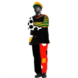 Black man with arms crossed wearing a patterned shirt and colorful cap against white background