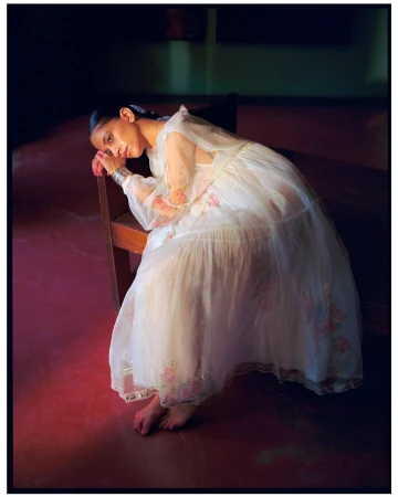 Woman in white sheer floral dress resting head on wooden bench in Mumbai, photographed by Tenzin Lhagyal.