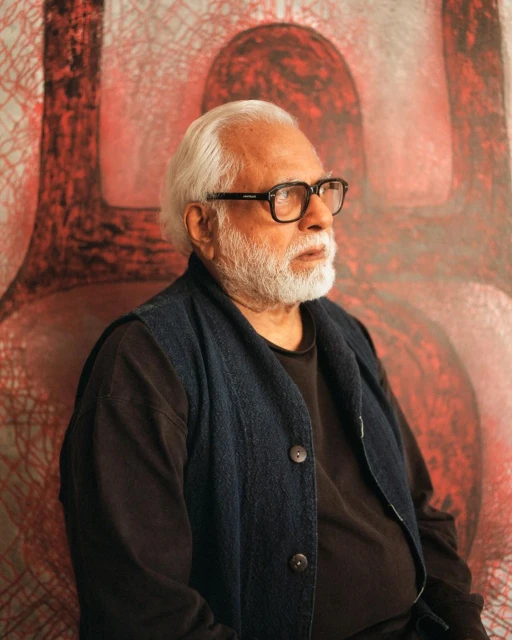 Older adult male portrait, side view, wearing glasses and a vest, with an abstract art background in red and white hues.