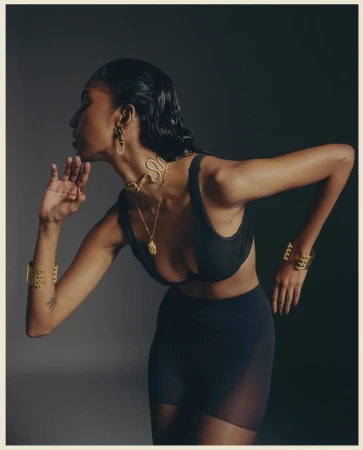 Profile of a woman wearing a black top and gold jewelry against a dark gradient background, photographed by Tenzin Lhagyal.