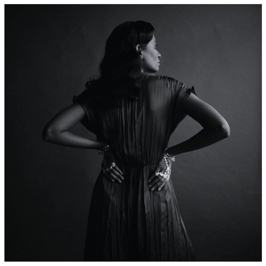 Monochrome portrait of a woman in a pleated dress wearing intricate hand jewelry, shot by Tenzin Lhagyal