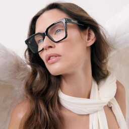 Close-up portrait of a woman wearing thick black eyeglasses and white feathered angel wings by Teresa Ciocia.