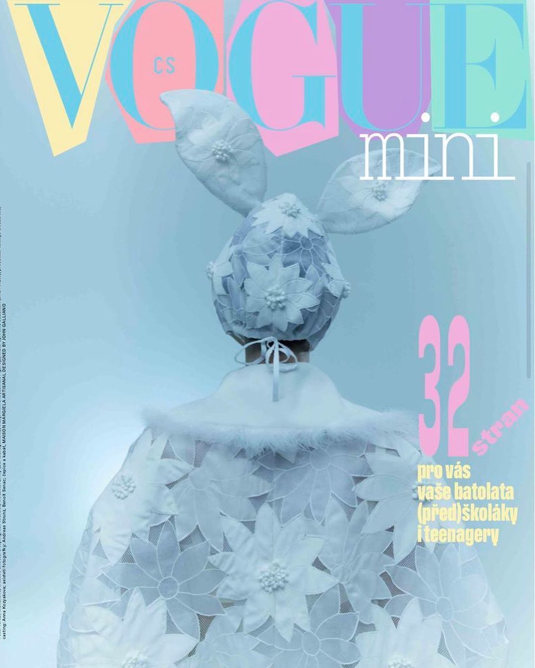Vogue Mini magazine cover features child model wearing a white floral lace bunny-eared hat and cape against light blue backdrop.