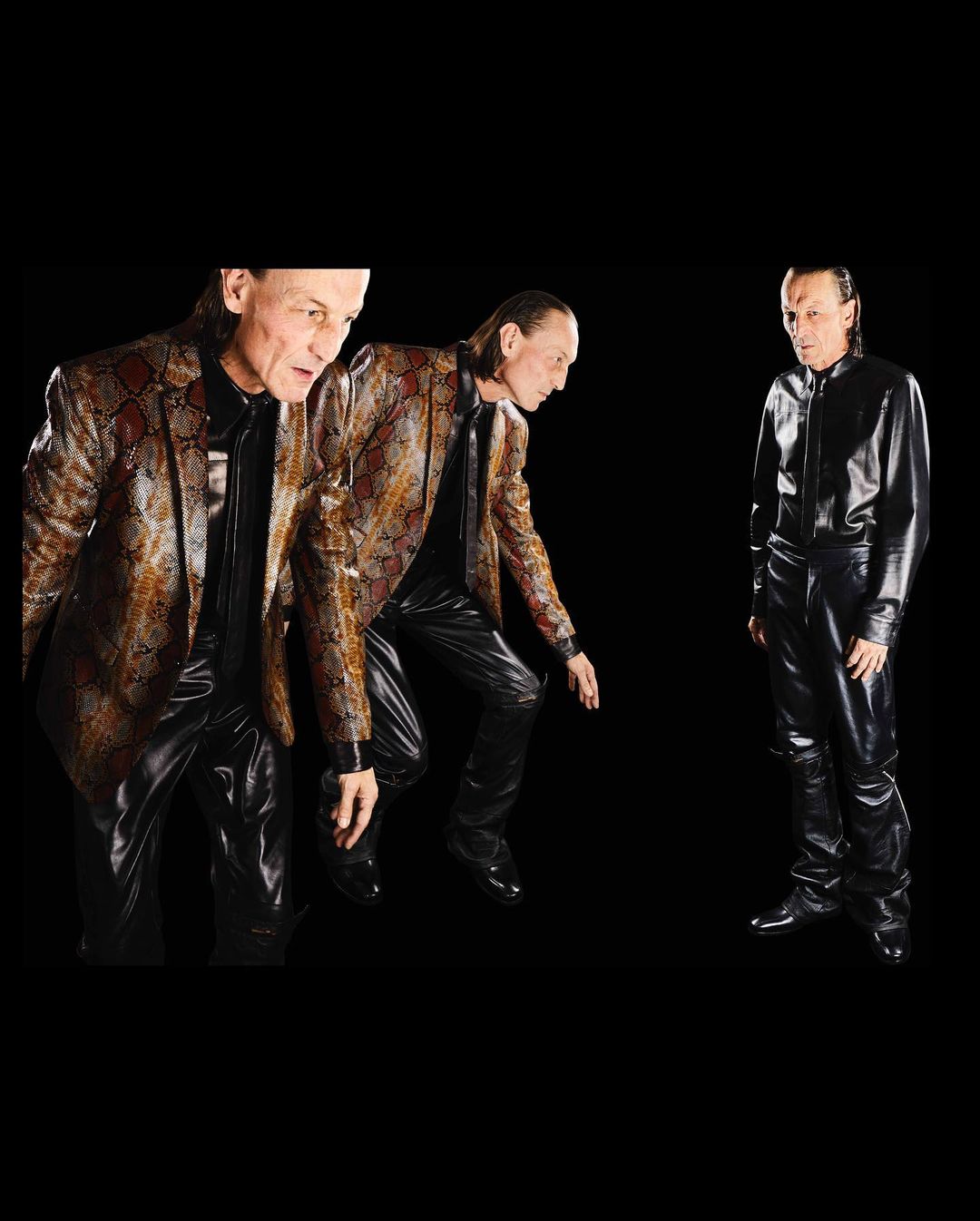 Conceptual fashion shot of a man in a snake-print blazer alongside a version of himself in a black latex outfit against a black backdrop.