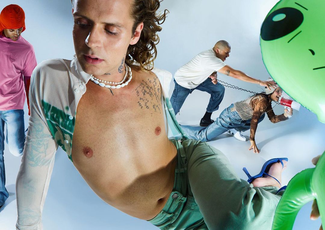Fashion-forward image featuring male models in a studio setting with soft lighting, showcasing diverse styles, including casual and avant-garde elements.